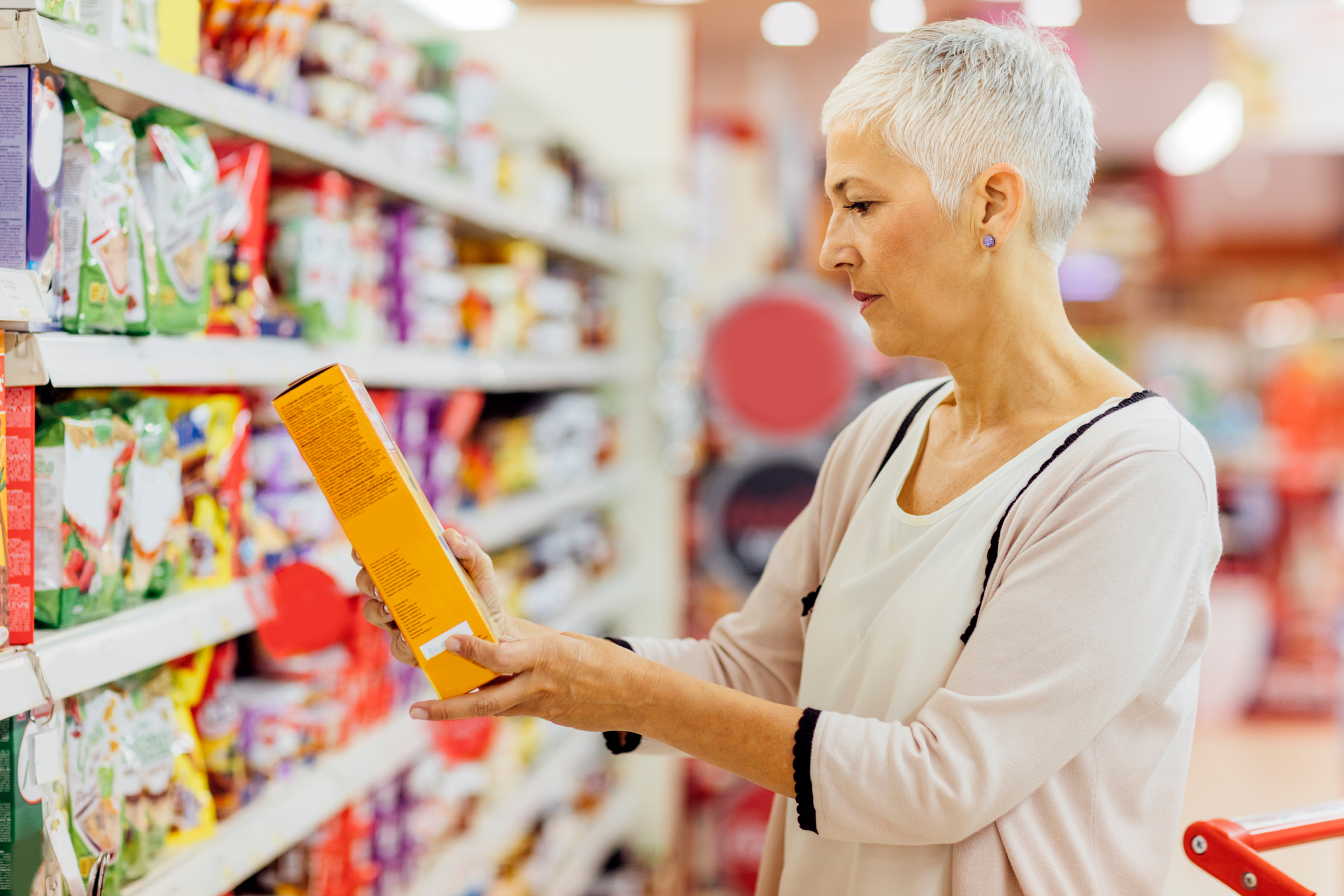femme comparant des céréales pour le petit-déjeuner dans un rayon de supermarché
